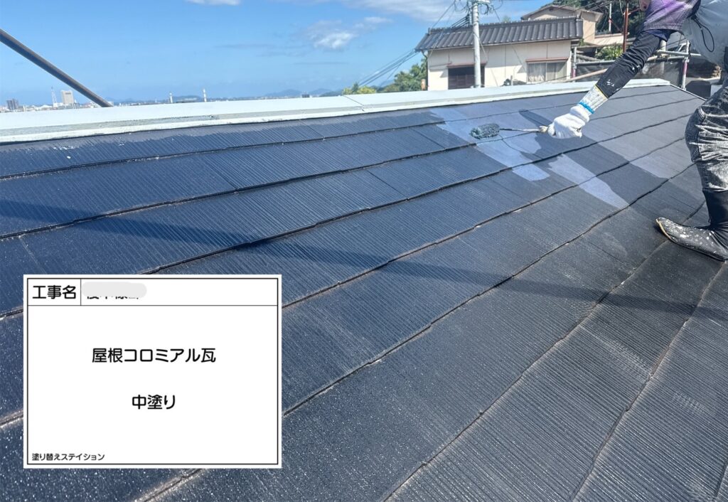 職人がローラーでコロニアル屋根の中塗り塗装を行っている施工風景
