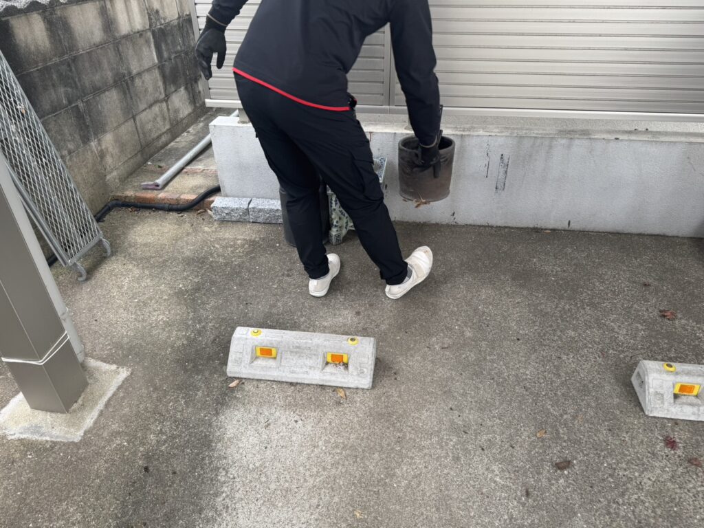 外壁塗装の足場組立前に、住宅の駐車場付近にある植木鉢やお荷物を丁寧に移動する作業風景