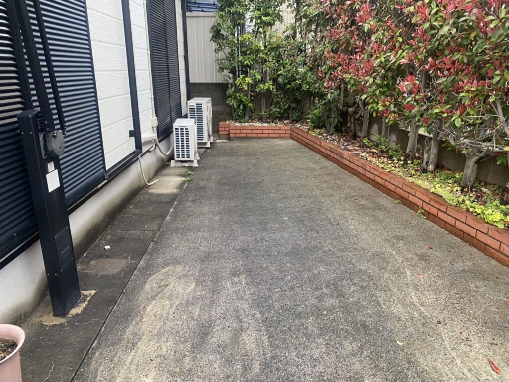高圧洗浄前の住宅駐車場。コンクリート床全体に黒ずみや汚れが見られる施工前の状態
