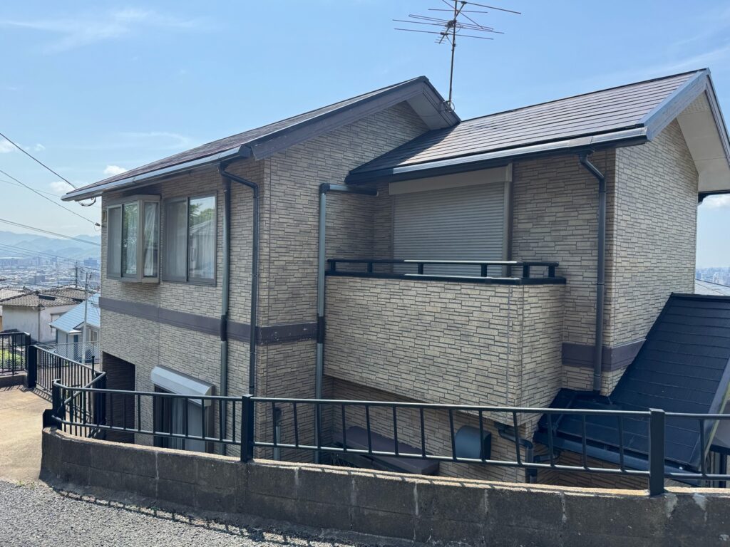 屋根・外壁塗装工事の施工前の2階建て住宅。外壁はツートンカラー、屋根は濃色