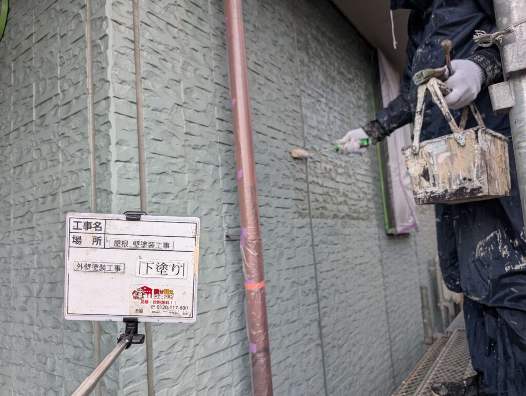 職人がローラーでサイディング外壁の下塗りを行っている作業風景
